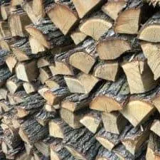 Winnipeg Firewood’s stacked firewood logs—cut with the bark intact and arranged in a neat pile—display both the natural cross-sections of the wood and its rugged outer surfaces.